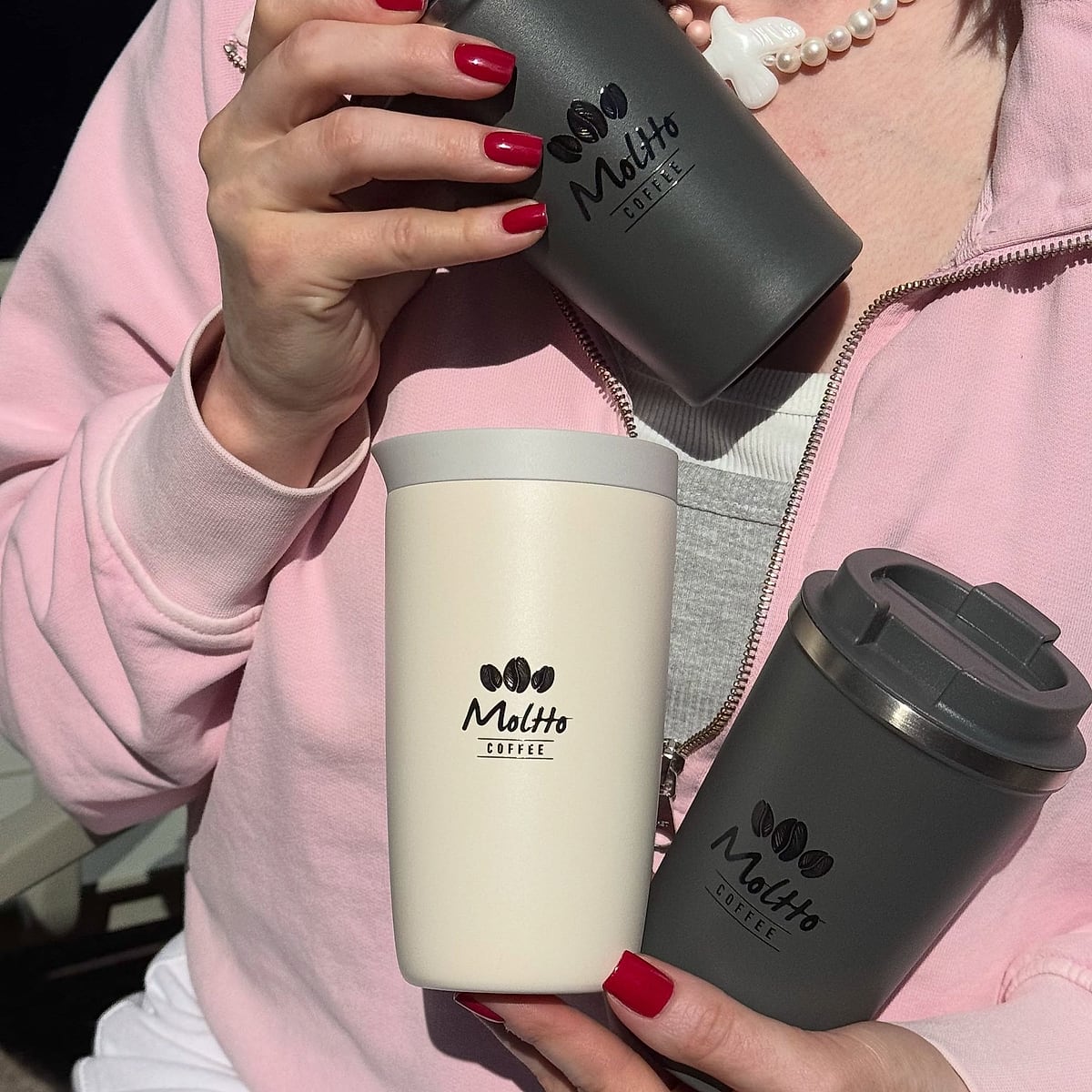 Three Moltto reusable cups held in the sun
